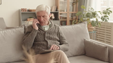 elderly man using phone and tablet at home