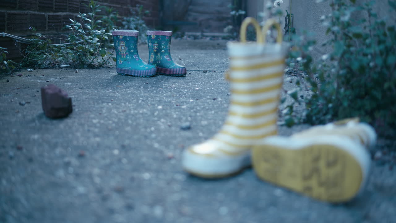 느린 팬 동안 작은 파란색 웰링턴 부츠에서 노란색 및 흰색 줄무늬 웰링턴 부츠까지 카메라 랙 초점