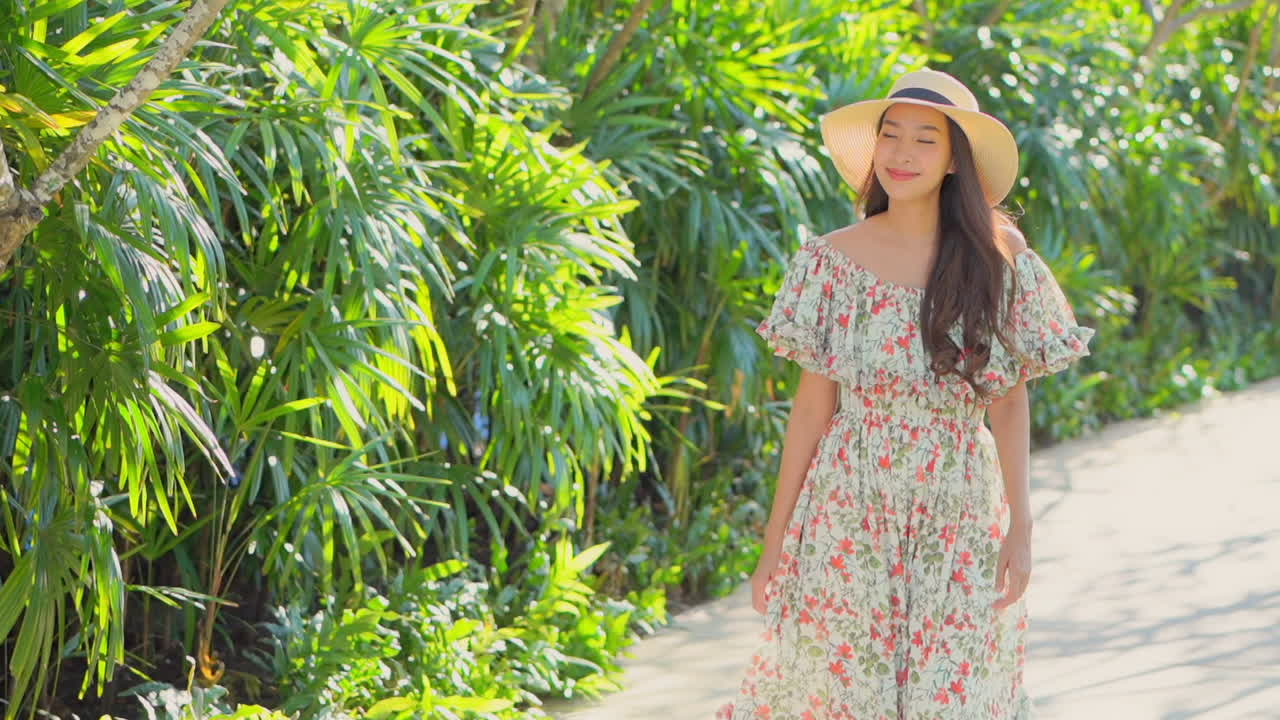 Asian millennial woman walking along a path in a garden, slow motion