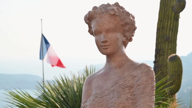 Statua in un parco con piante tropicali a Mentone, Francia. Mare sullo sfondo