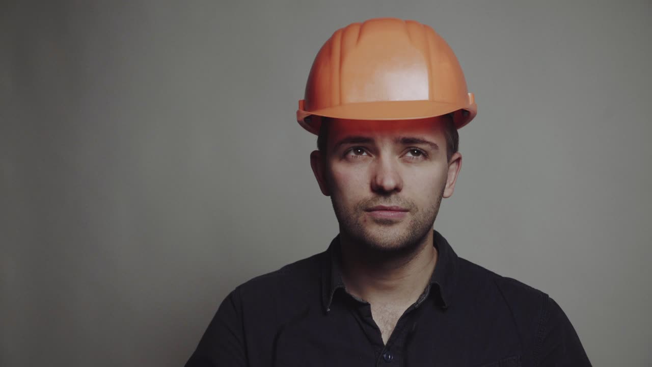 Portrait of young engineer with helmet. Young construction worker in hard hat on gray background
