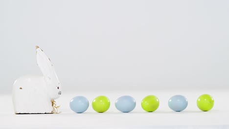 huevos de pascua en una fila con un conejo de pascua de juguete