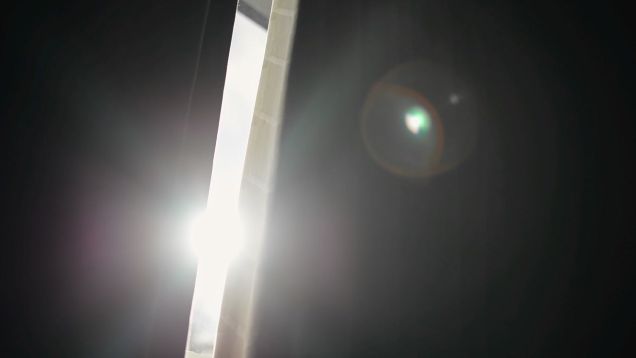 Sol da manhã brilhando através de cortinas parcialmente abertas, causando reflexos na lente