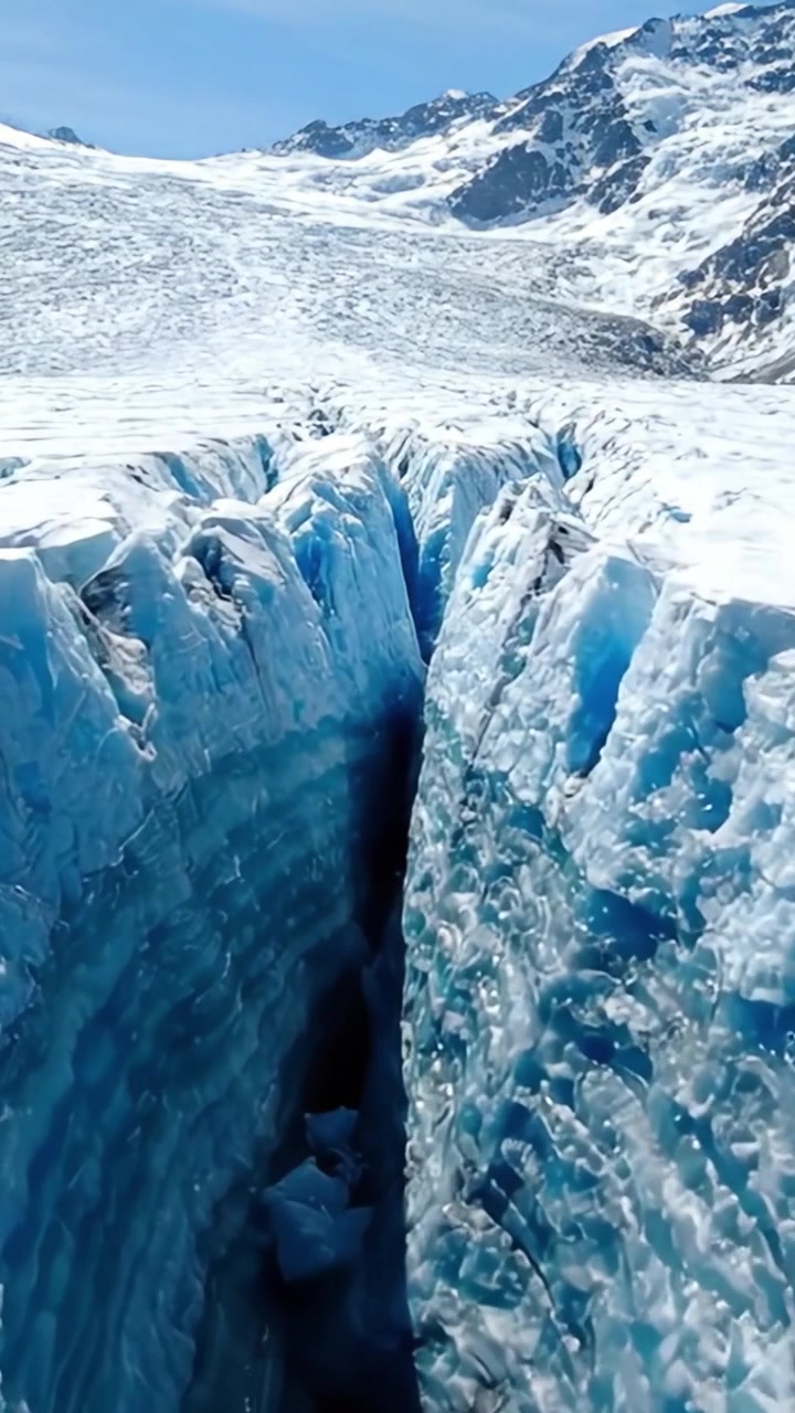 Majestuosa grieta glaciar: Capturando la impresionante belleza de profundas grietas de hielo en un impresionante paisaje glaciar bajo cielos azules claros