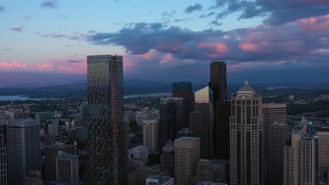 Toma-Aérea-Alejándose-Del-Vasto-Horizonte-Del-Centro-De-Seattle-Durante-Una-Puesta-De-Sol-Rosa-Fresca