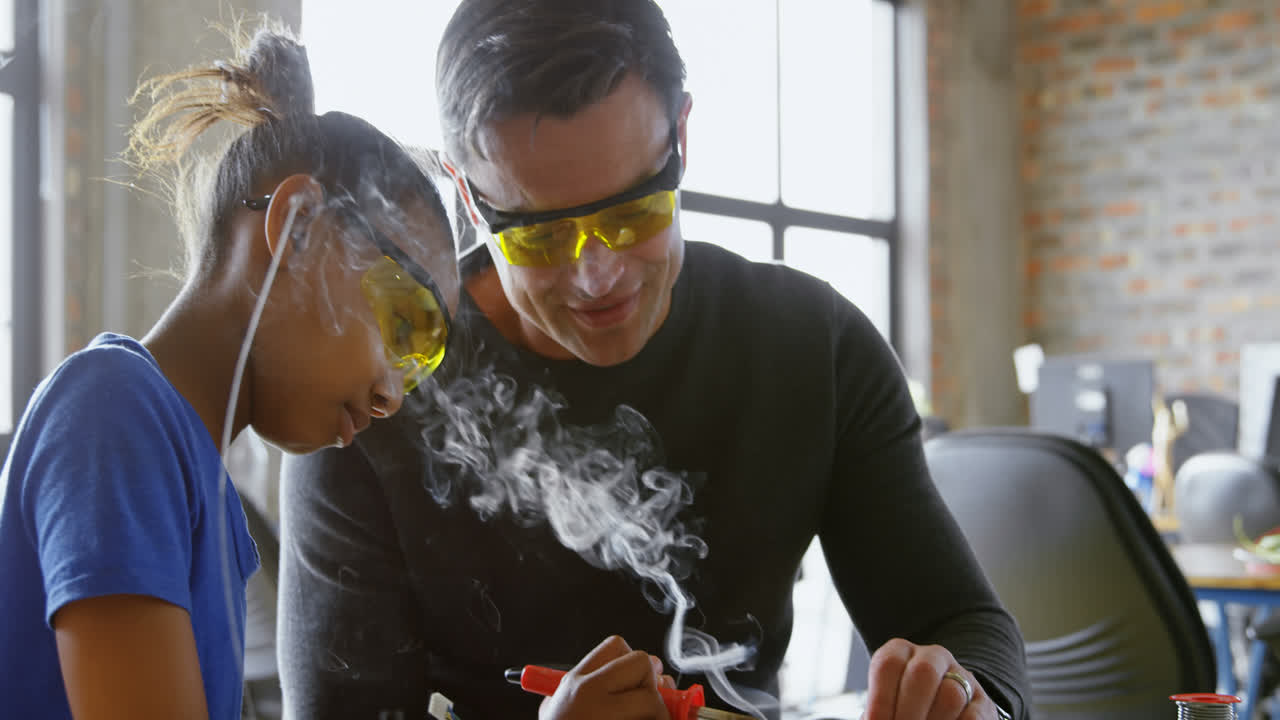 padre enseñando a su hija sobre soldadura de hierro 4k
