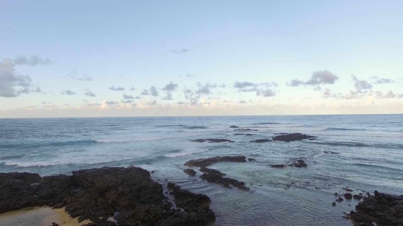 Volare sopra pietre vulcaniche nere nell'acqua costiera dell'oceano.