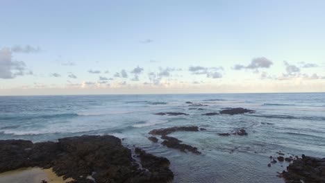 Flying-over-black-volcanic-stones-in-coastal-ocean-water