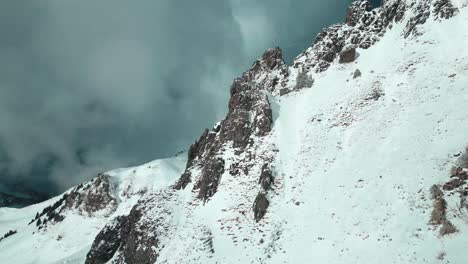 Aerial-drone-shot-flying-horizontally-along-the-snow-covered-mountain-slope-in-Engelberg-Brunni-bahnen-along-the-Swiss-alps-in-Switzerland-on-a-cold-winter-day