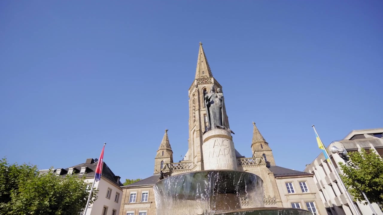 Vista frontale della storica Chiesa di San Ludovico con la sua alta guglia in pietra e fontana nel centro della città di Saarlouis, Germania