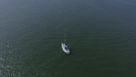 back aerial drone view of a yacht sailing in the blue sea.