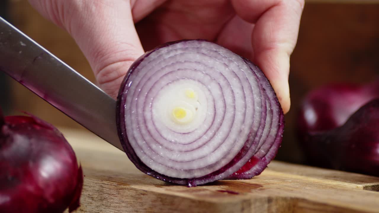 Hands men cut red onion in rings.