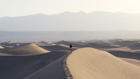 ultra slow motion shot of woman balancing on sand dune in the desert in death valley national park in california, usa