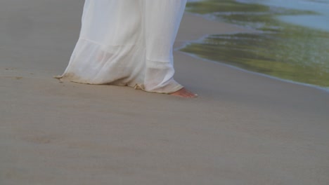 Los-Pies-Caminando-En-La-Arena-De-La-Playa-Antes-De-Que-La-Cámara-Ascendente-Revele-A-Una-Mujer-Joven-Con-Un-Vestido-De-Playa-En-La-Playa-En-Un-Día-Soleado