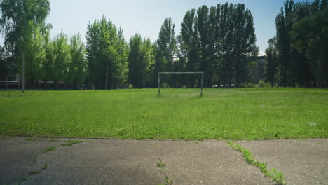 four siblings are actively playing football on a paved road, with one kicking the ball while others engage in the game