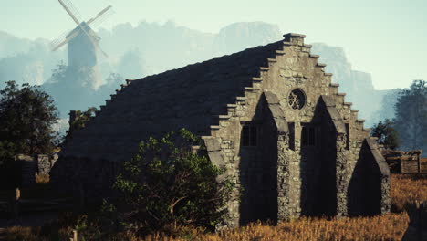 medieval church with windmill in a foggy landscape