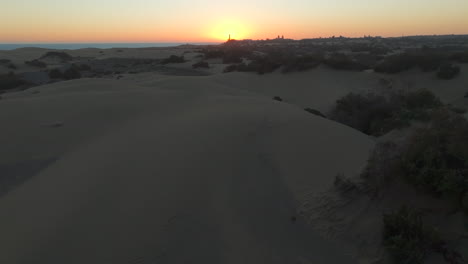 Flug-über-Die-Großen-Dünen-Des-Strandes-Von-Maspalomas-Bei-Sonnenuntergang-Und-Mit-Dem-Leuchtturm-Von-Maspalomas-Als-Hintergrund