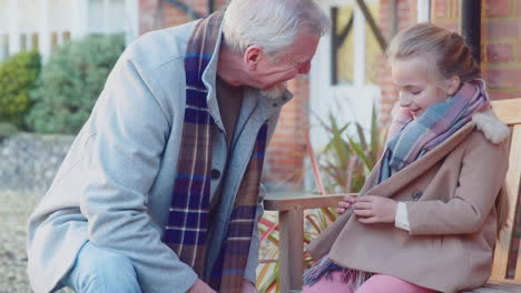 grandfather helping granddaughter to tie shoelaces as they get ready to go on walk with pet dog