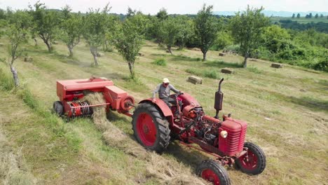 antena de un granjero con un tractor que lleva una empacadora de heno a través de un campo
