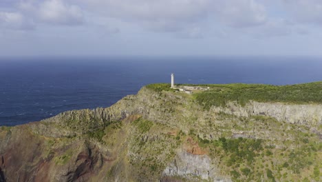 drone footage of a lighthouse on the top of dramatic cliffs with the atlantic ocean in the background in sao jorge island, azores, portugal