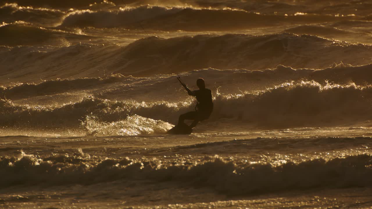 In rays of setting sun, kitesurfer enjoys freedom and excitement of kiteboarding, feeling rush of adrenaline with every movement