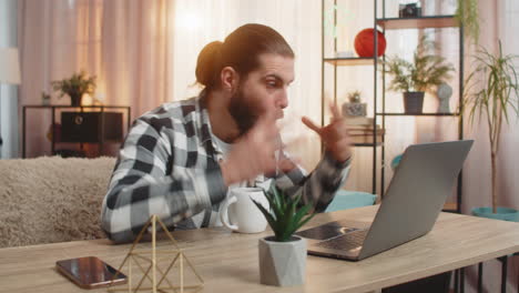 young man browsing laptop shop at home coffee by side exclaim wow huge discount joyful surprise