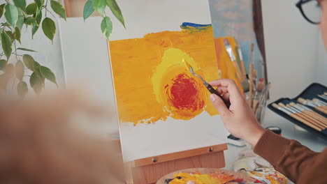 an unrecognizable man painting with a spatula on a canvas 2