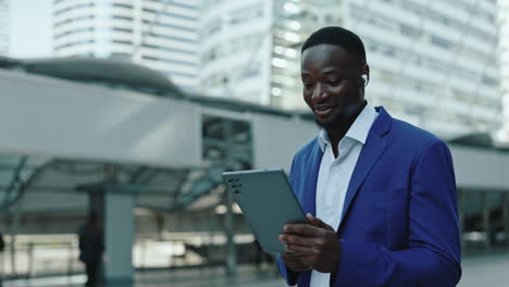smiling businessman using tablet and earbuds in city