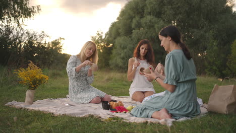 a group of young women concentrates on drawing patterns on clay products with the help of tools decorate molded objects in a meadow in nature in an open space. general view