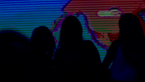 silhouettes of women in a night club with colorful background