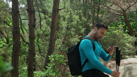 hombre excursionista con mochila y palos de trekking se levanta y comienza a caminar después de un poco de descanso en las montañas bosque - seguimiento gimbal cámara lenta