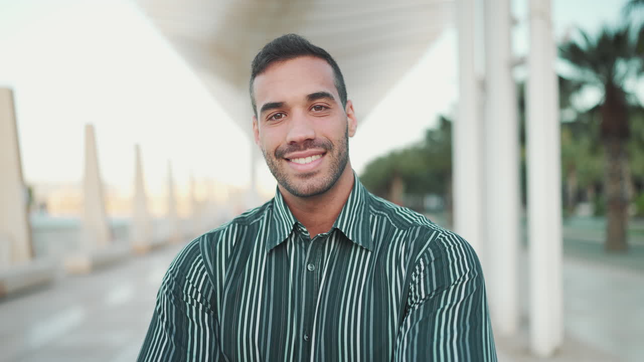 Young man smiling at the camera outdoors.