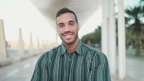 young man smiling at the camera outdoors.