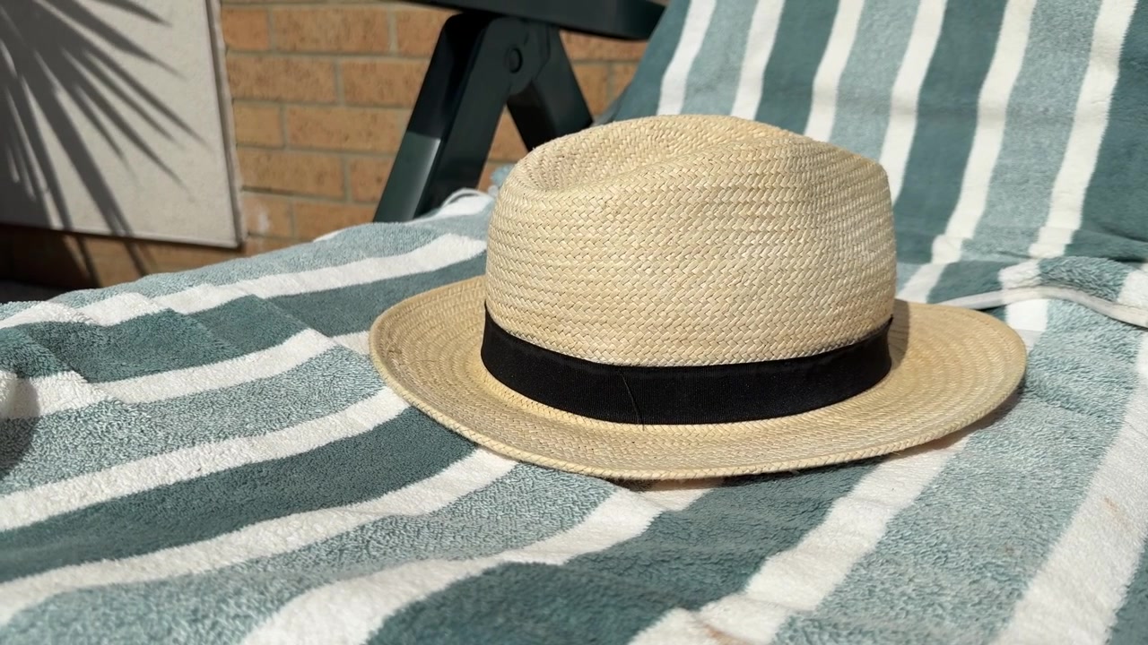 Cappello di paglia da sole appoggiato su una sdraio in un giardino estivo.