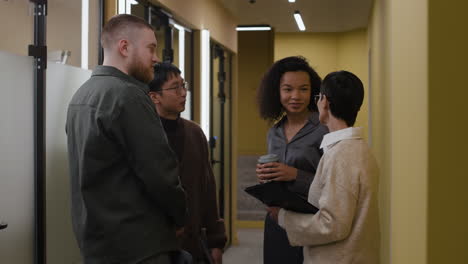 group of coworkers discussing in an office hallway