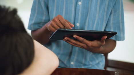 chest to waist shot of man wearing blue shirt tapping tablet screen with two fingers, highlighting precision gesture input and fabric detail in scene framed at mid torso with warm ambient lighting glow