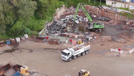 aerial footage of trucks and machinery in a gold coast junkyard. bright daylight highlights the industrial scene and active operations