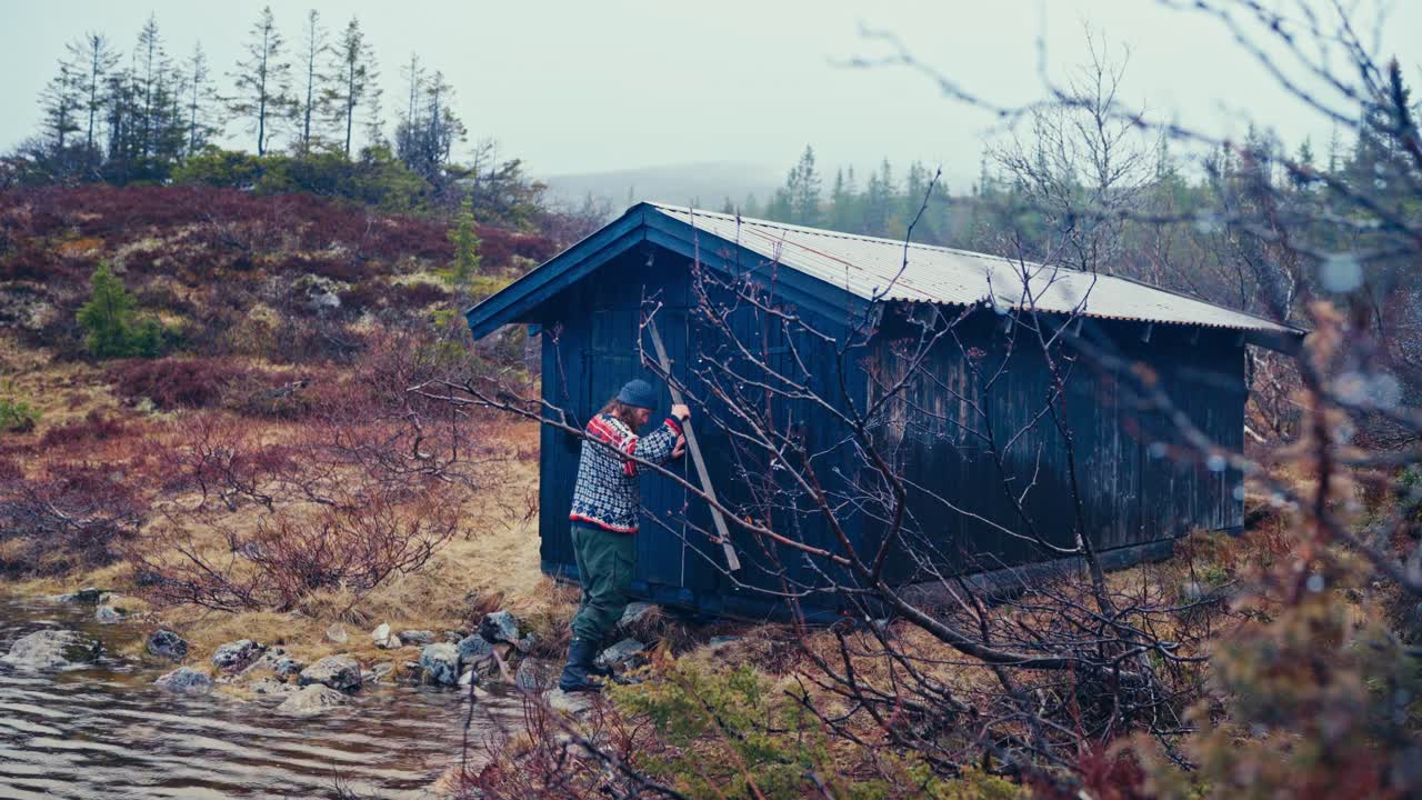 En man förvarar en roddbåt inne i skjulet. Vidvinkelbild