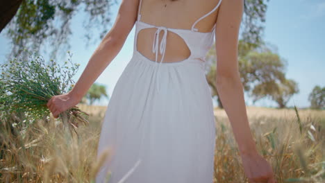 woman body walking spikelets field back view. happy lady spinning with bouquet