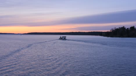 cinematic view of a motor boat navigating though calm waters at a beautiful orange sunset