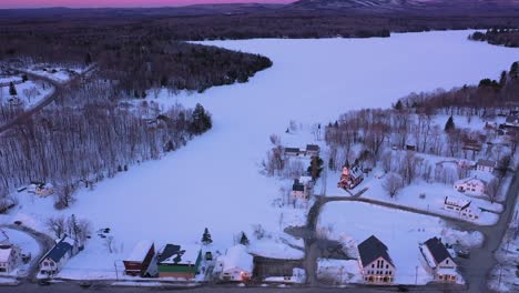 aerial slide and tilt to reveal a small town on the shore of a frozen lake during an amazing sunrise