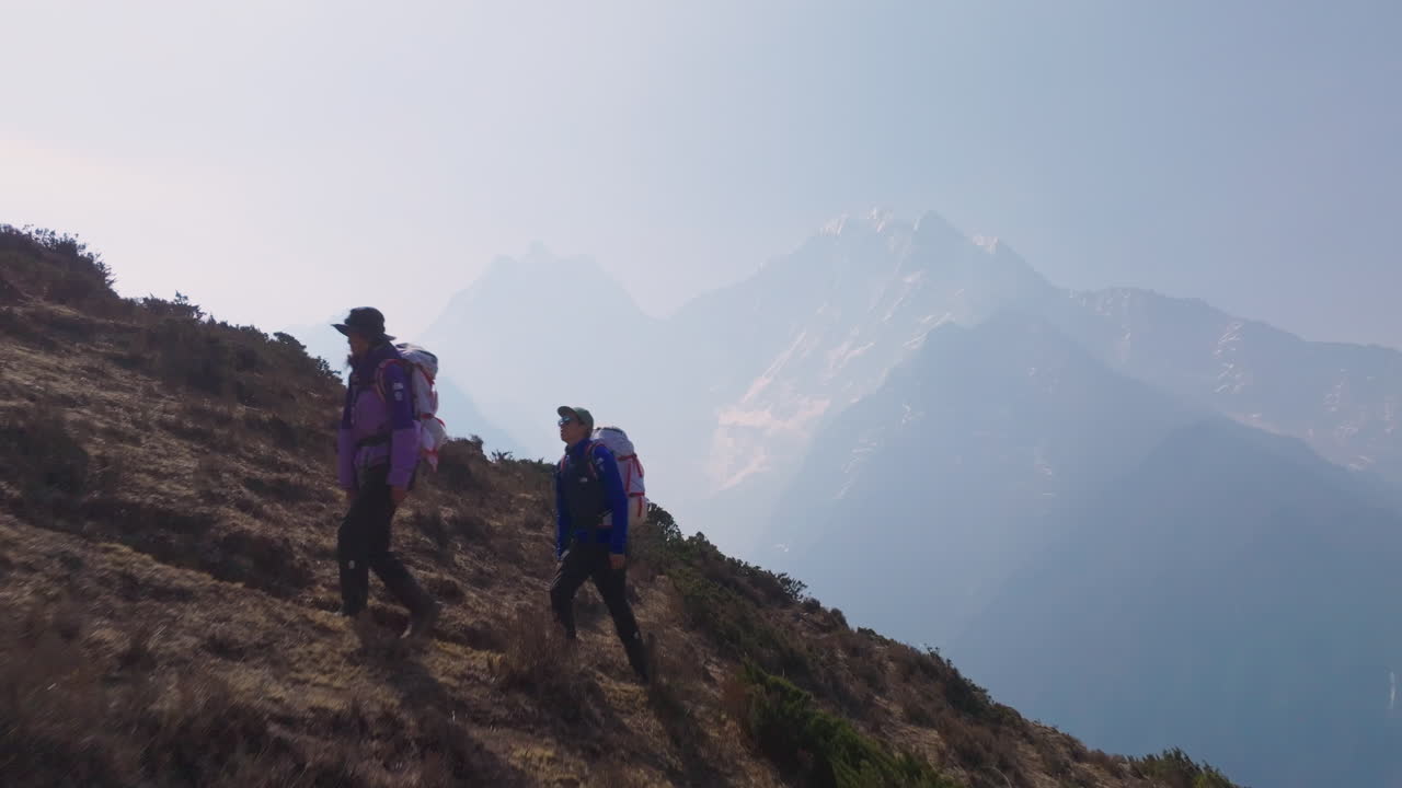 Drone shot of tourist trekking uphill from Phortse to Dingboche, Everest region; mountain range hidden in clouds, scenic yet unclear weather