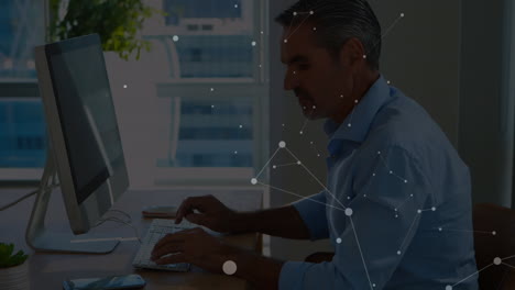 animation of connected dots on caucasian man talking on cellphone and working on compute
