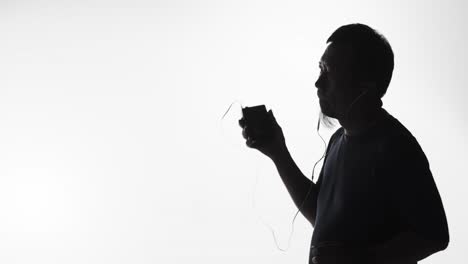 silhouette of a man listening to music on a smartphone, vintage tape player or smart device