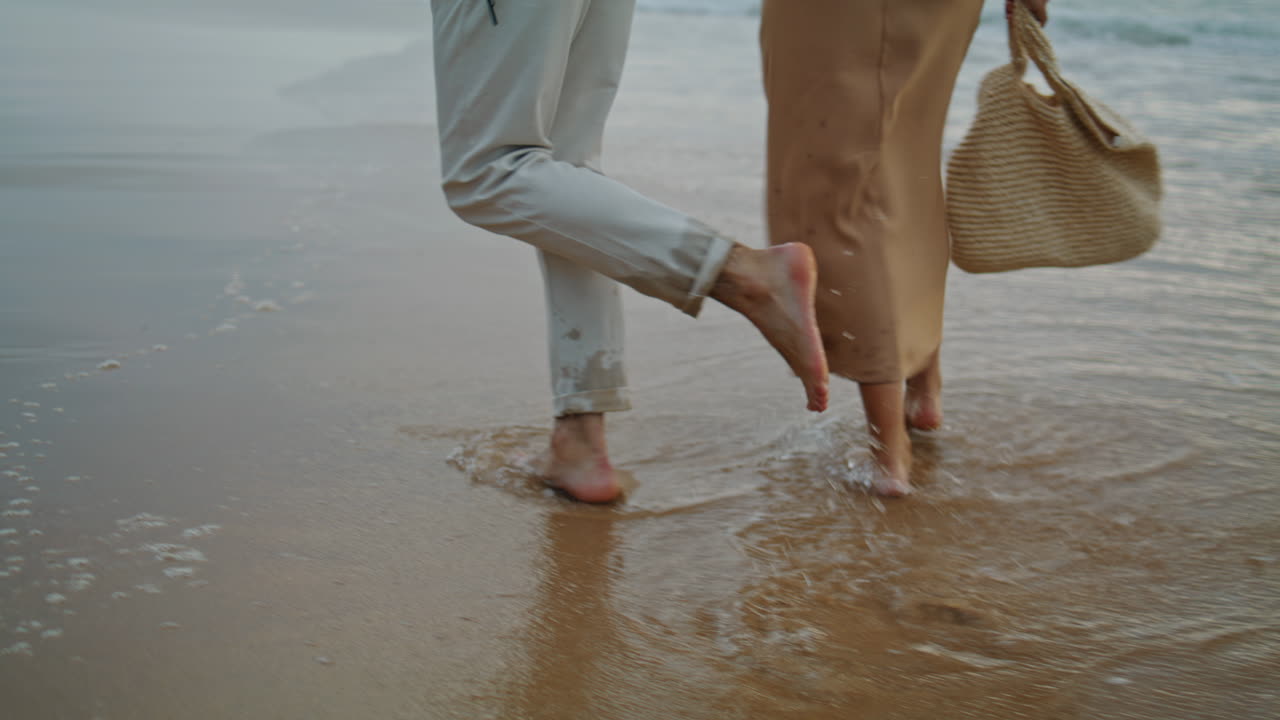 pareja de piernas cruzando la orilla del mar en primer plano de verano. tiernos cónyuges disfrutando del océano