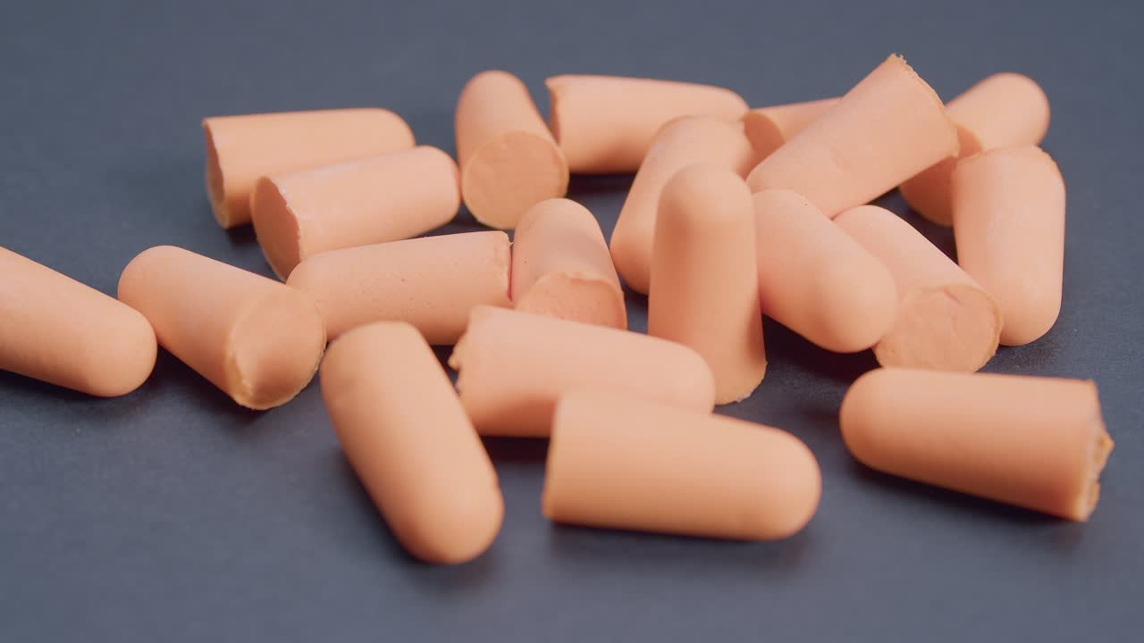 Orange ear plugs, hear protection on dark gray background, rotation view