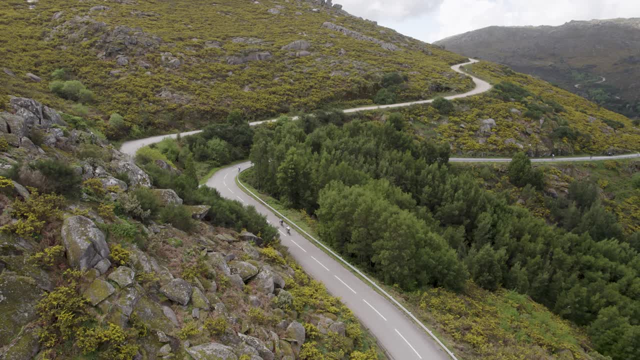 Vista aérea de ciclistas subindo uma estrada montanhosa sinuosa na Serra d’Arga, Viana do Castelo, Portugal
