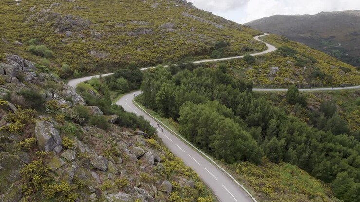 Vista aerea di ciclisti che scalano una strada di montagna tortuosa a Serra d’Arga, Viana do Castelo, Portogallo