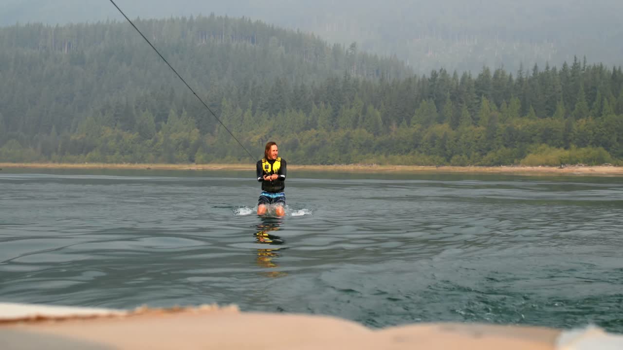 도시 강 4k에서 웨이크 보드에 트릭을하는 백인 젊은이의 앞면