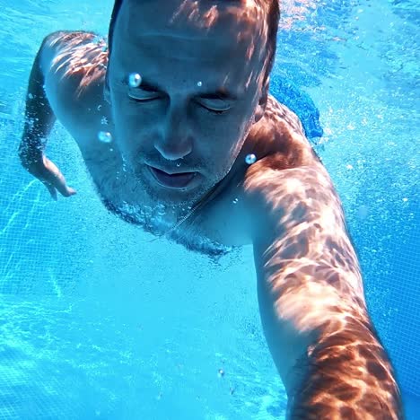 man jumping into the swimming pool. healthy man holding underwater camera and jumping into blue water of the pool. summer vacation.